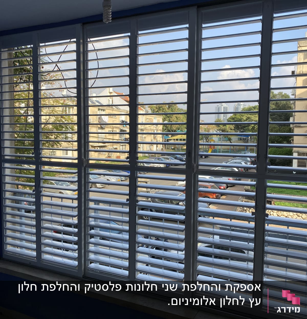 תריסים לבנים על חלון גדול עם נוף עירוני